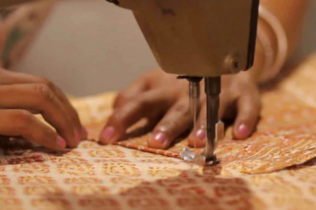 artesã tailandesa costurando na máquina uma calça thai 