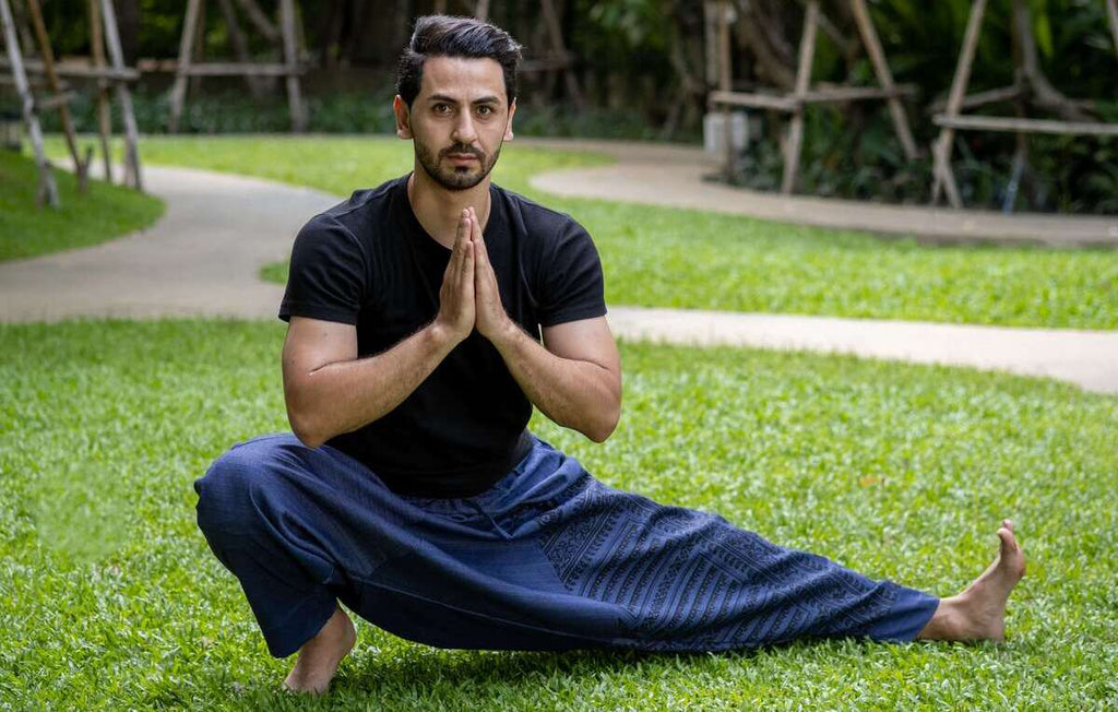 homem fazendo yoga na grama usando calça thai