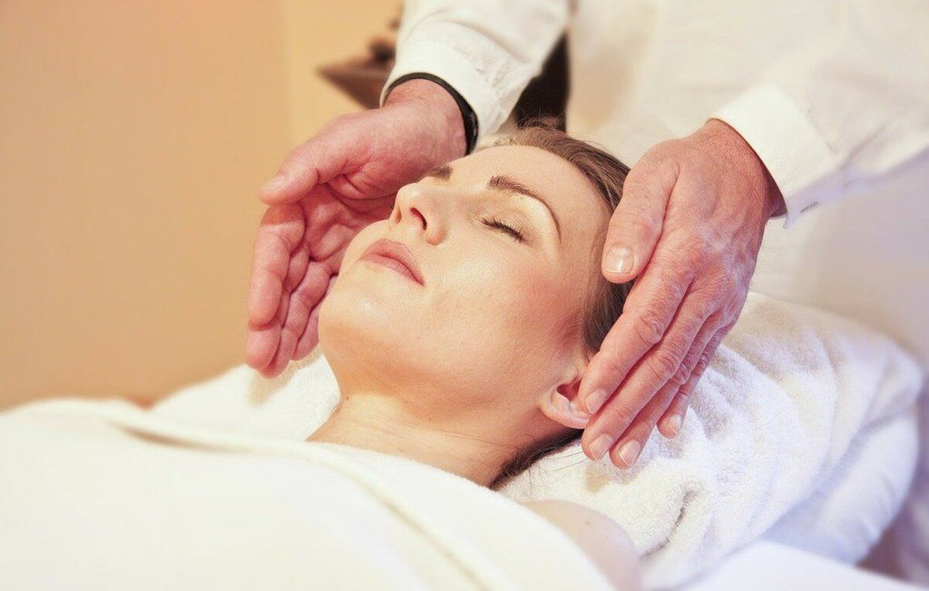 mãos de um homem aplicando reiki em torno da cabeça de uma mulher