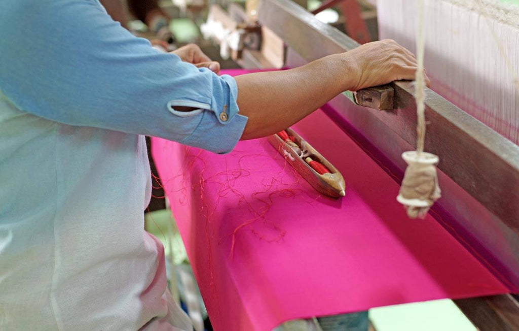 mulher trabalhando em tecelaria com tecido seda cor de rosa