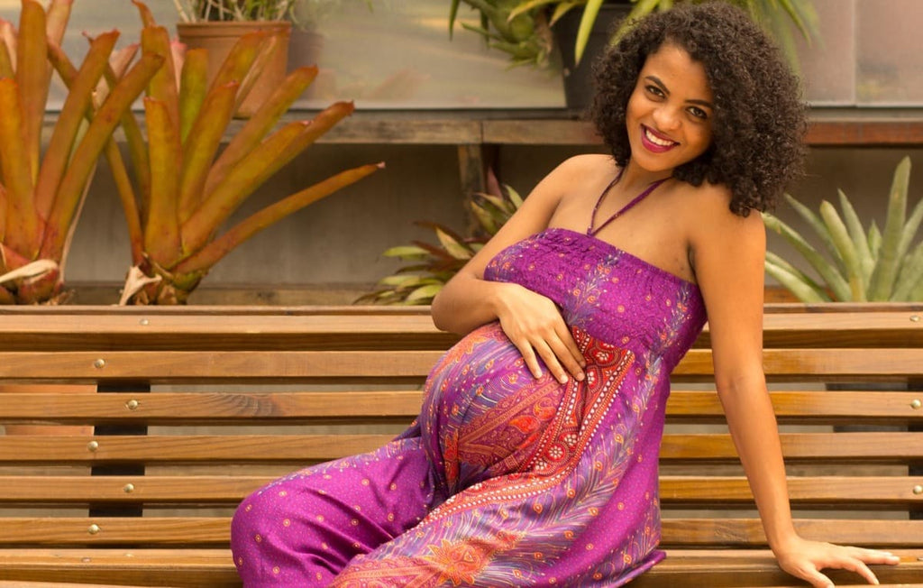 mulher grávida sentada em banco usando macacão como roupas para gestantes