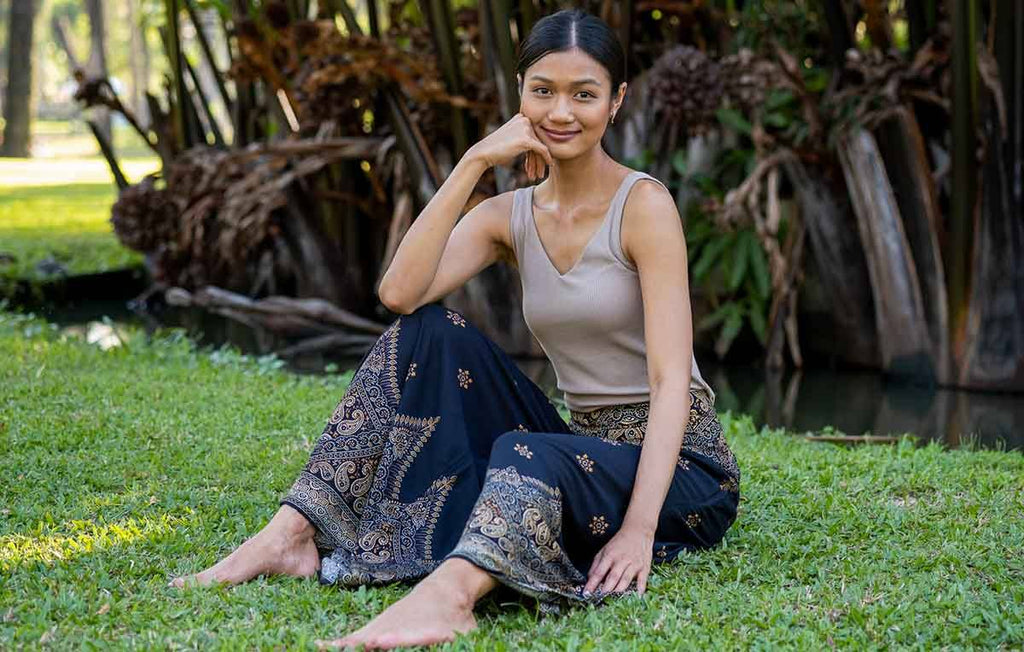 mulher sentada no parque usando regata e calça pantalona estampada